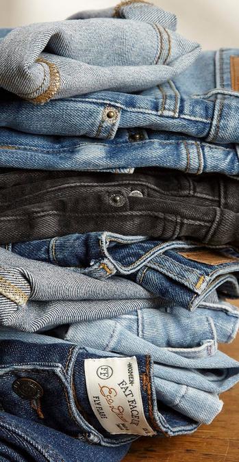 A stack of women's denim jeans in a variety of blue & black washes.