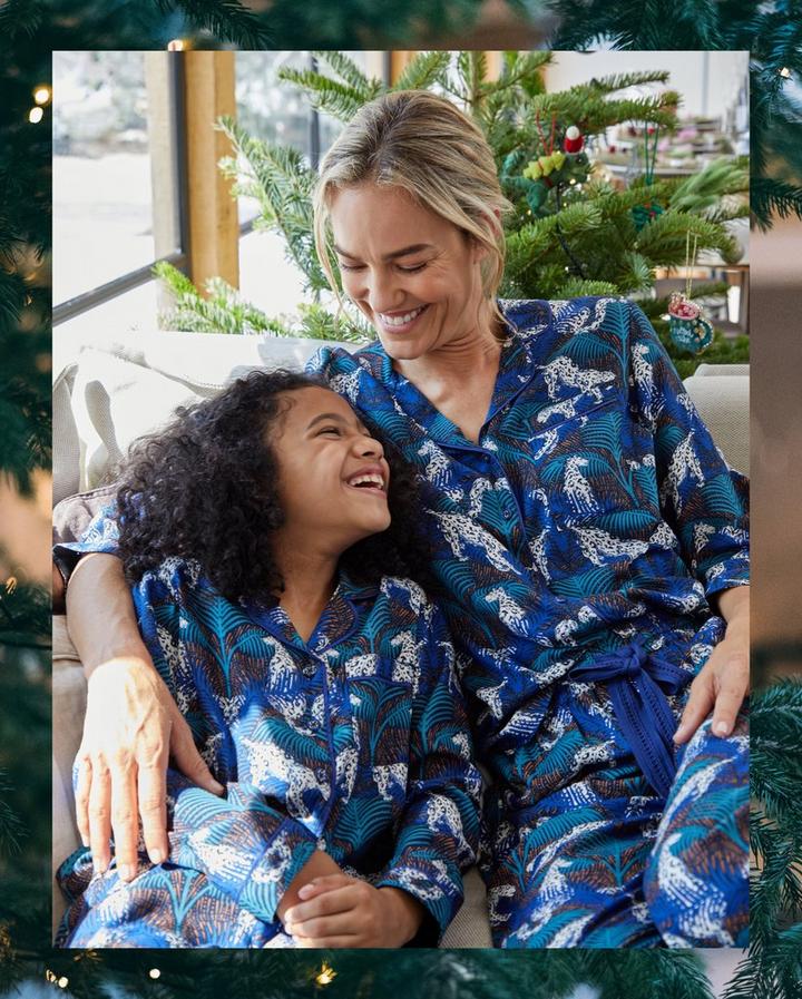 A girl and a woman in matching blue snow leopard patterned PJ sets.