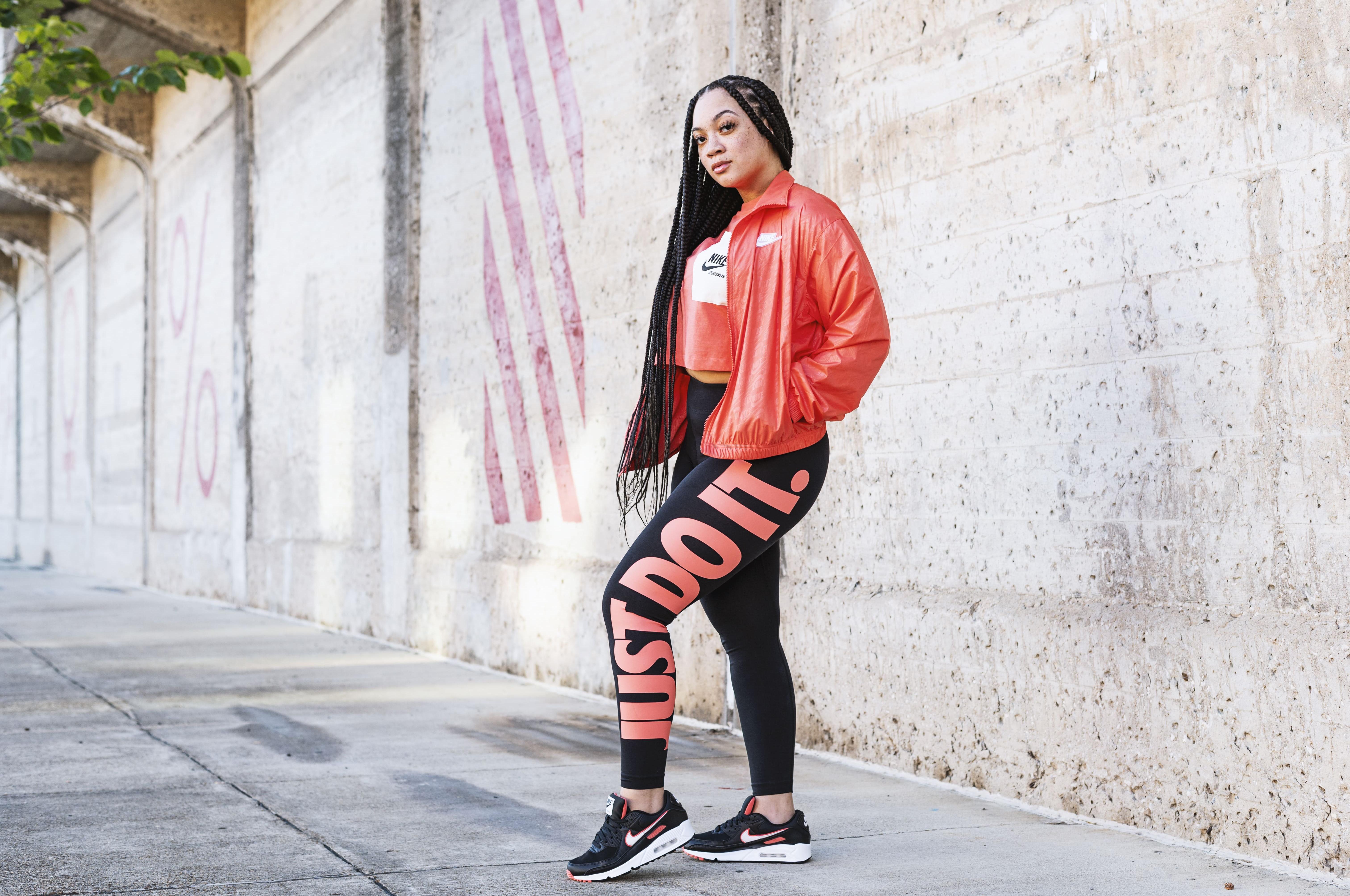 Woman in Nike Air Max 90s, Nike leggings, Nike crop top, and Nike windrunner.