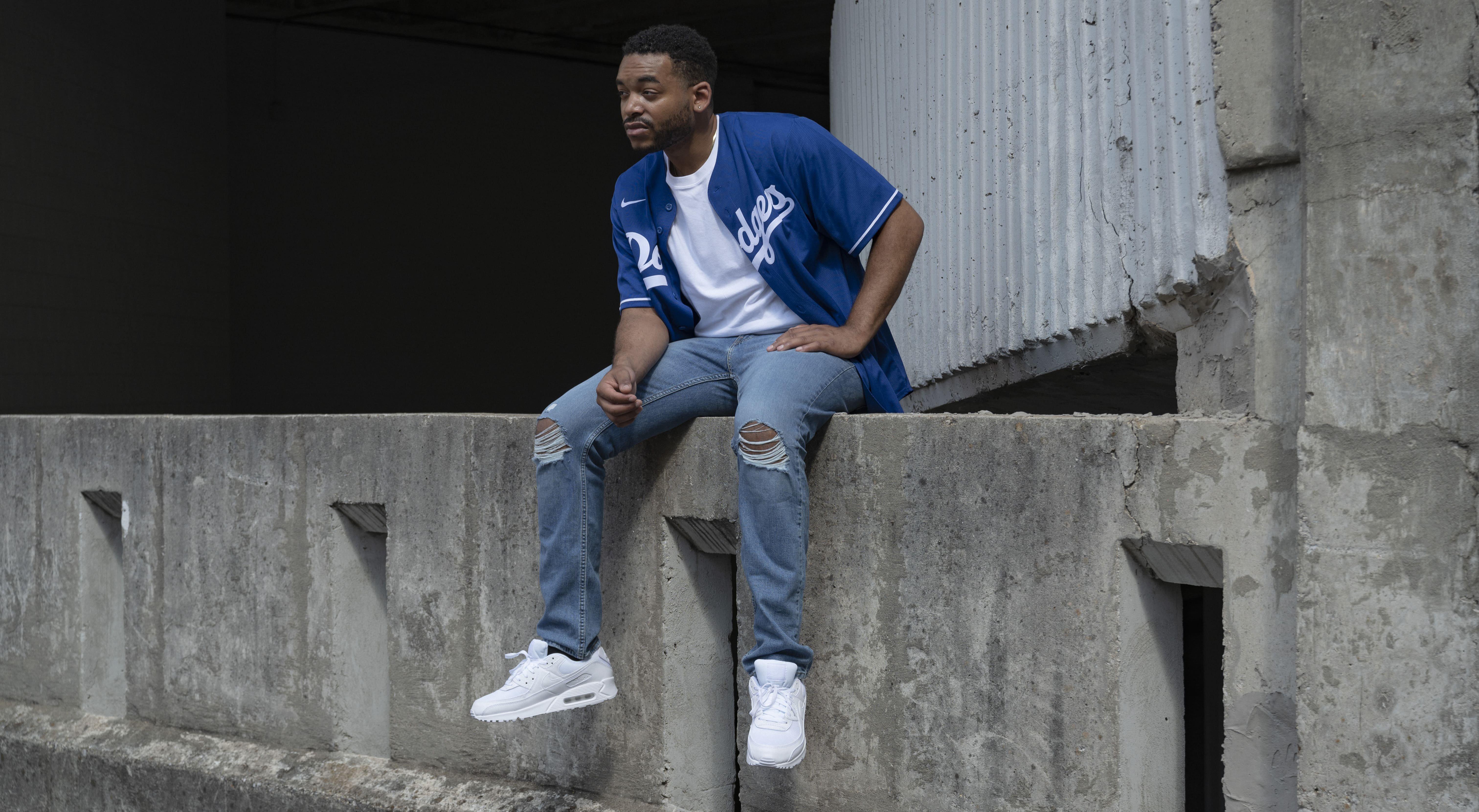 man in white air max 90, blue jeans, and dodgers jersey