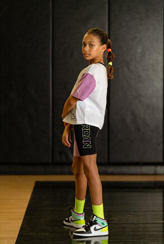 Air Jordan girls bike shorts and cropped colorblocked tee with neon green socks and multicolored AJ 1 Mids.