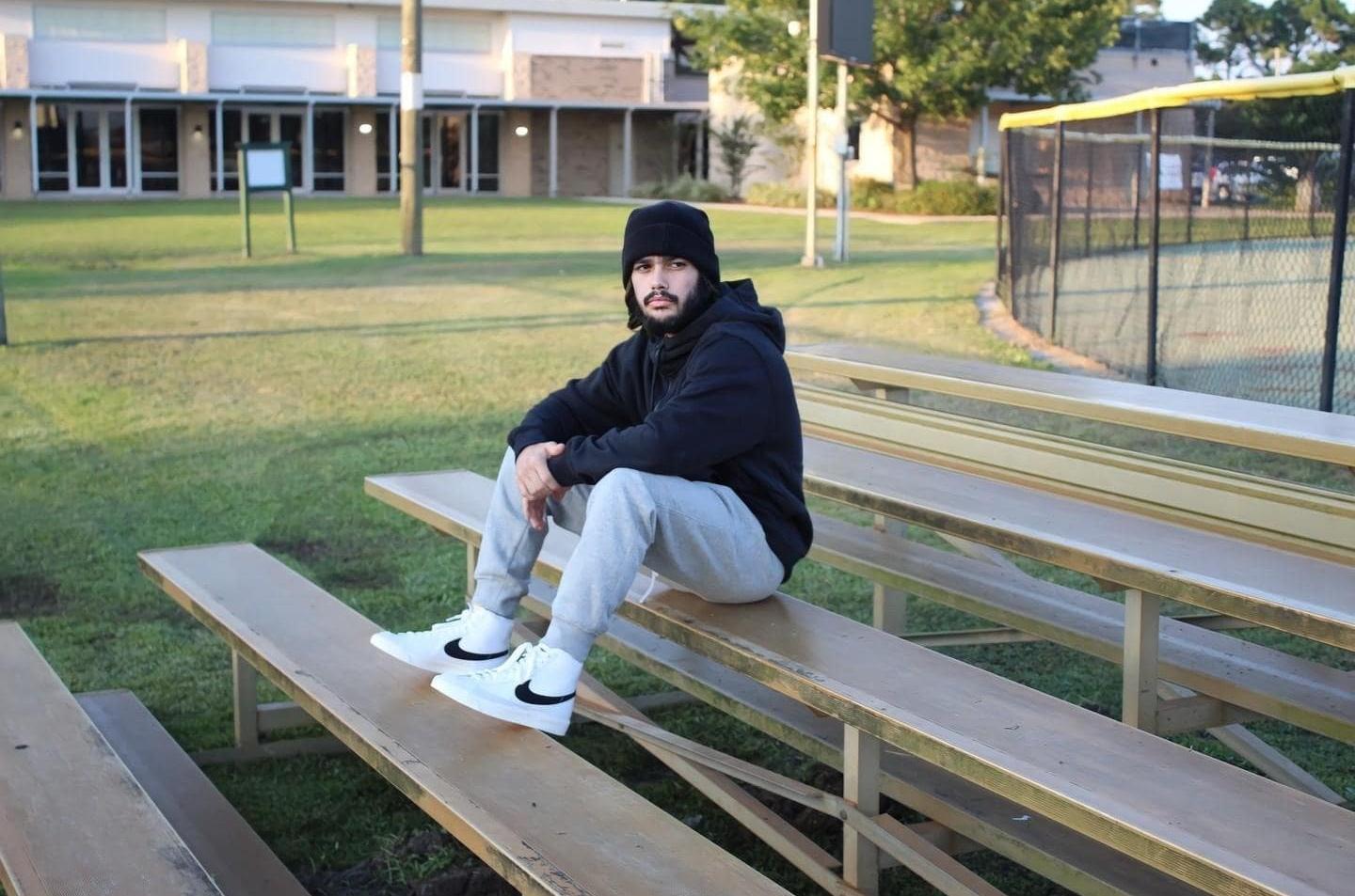 Man in grey joggers, black hoodie, black beanie and white Nike Blazers
