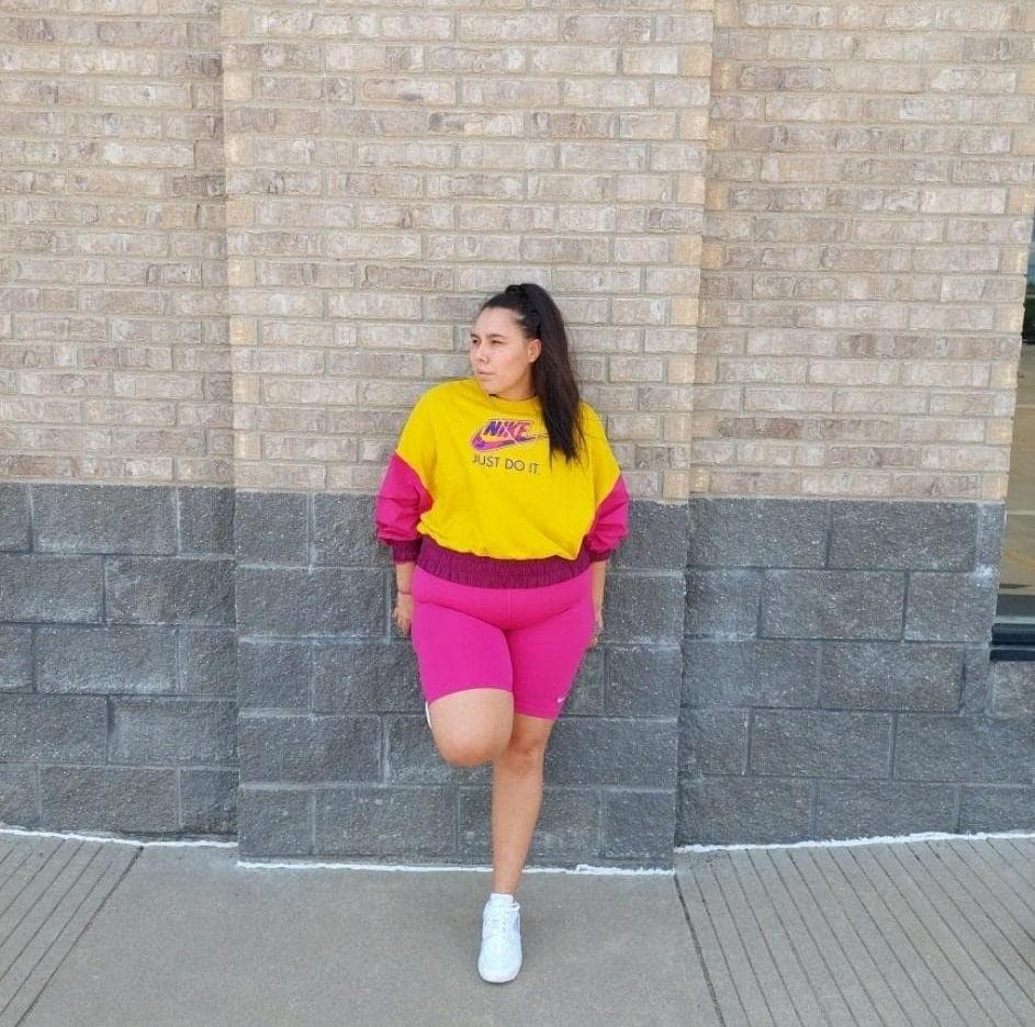 Woman in pink Nike bike shorts, Nike sweatshirt, and white Nike sneakers.