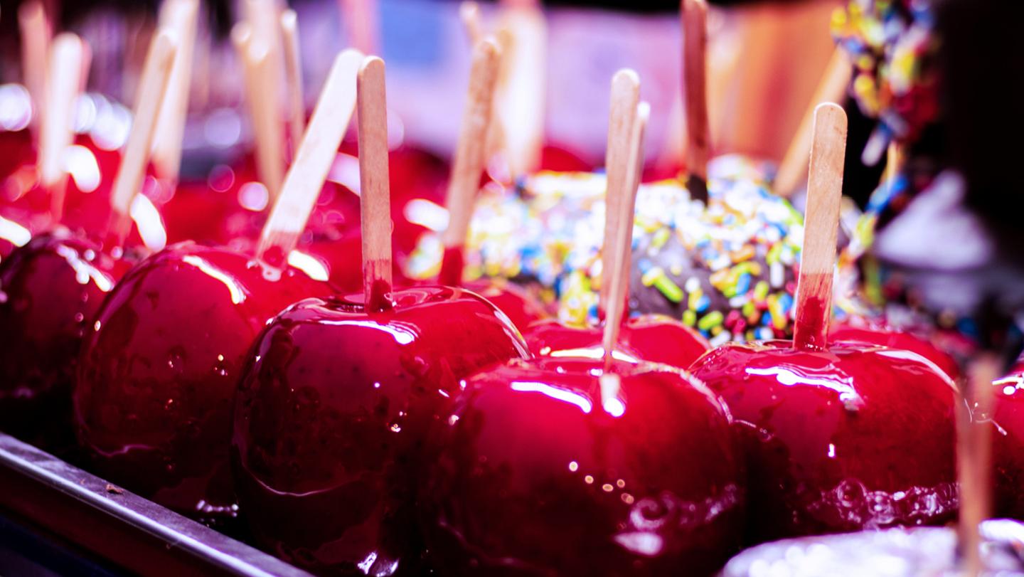 Red and glossy sticky toffee apples, places on a tray ready for eating