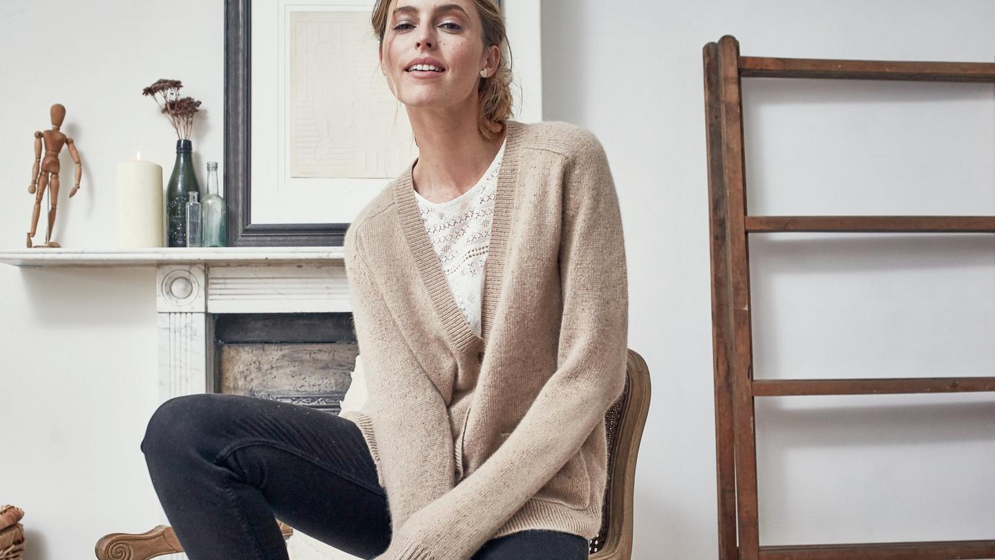 The Sophie Cardigan from FatFace with 5% cashmere, worn on a model sitting in a neutral colour living room