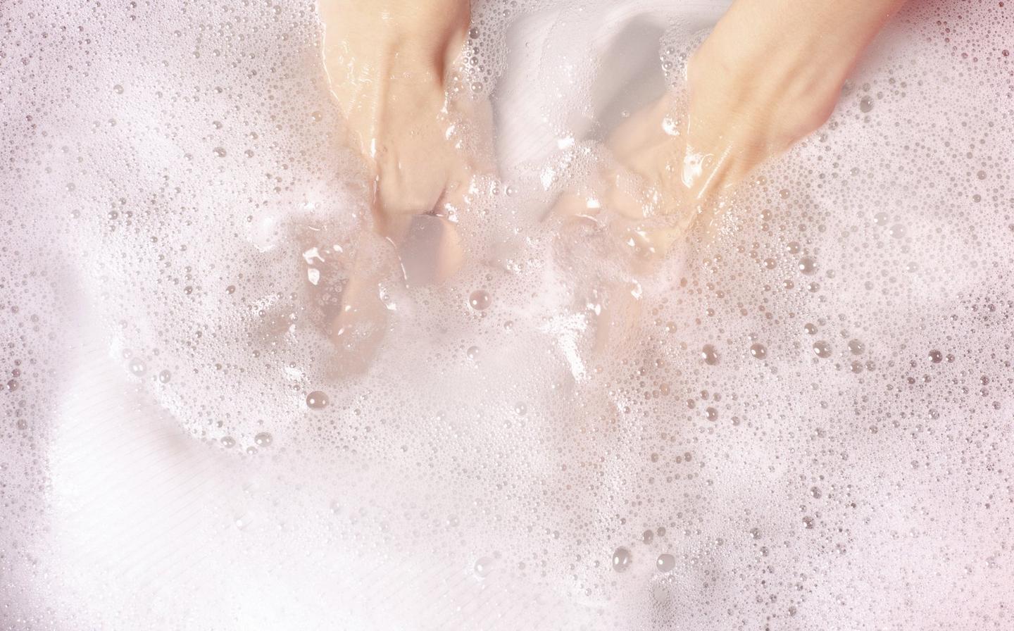 A cashmere knit being hand washed in soapy cool water with a non-bio detergent