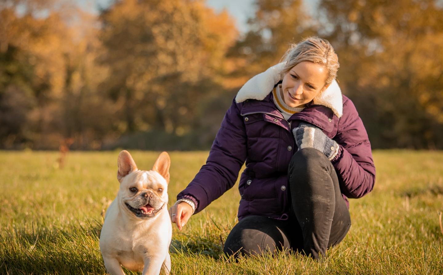 Steph, who works at FatFace HQ, wearing the Poppy Puffer Jacket while playing with her dog Dax in a field