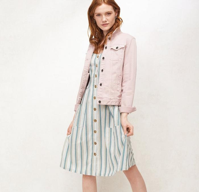 A pink denim jacket worn with a green stripe dress from FatFace, worn by a red-haired model
