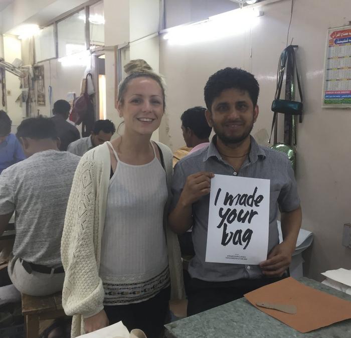 A woman stood next to a man holding a, I made your clothes, sign
