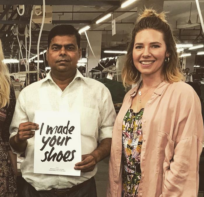 A man holding a I made your shoes sign stood next to a woman in a pink shirt.