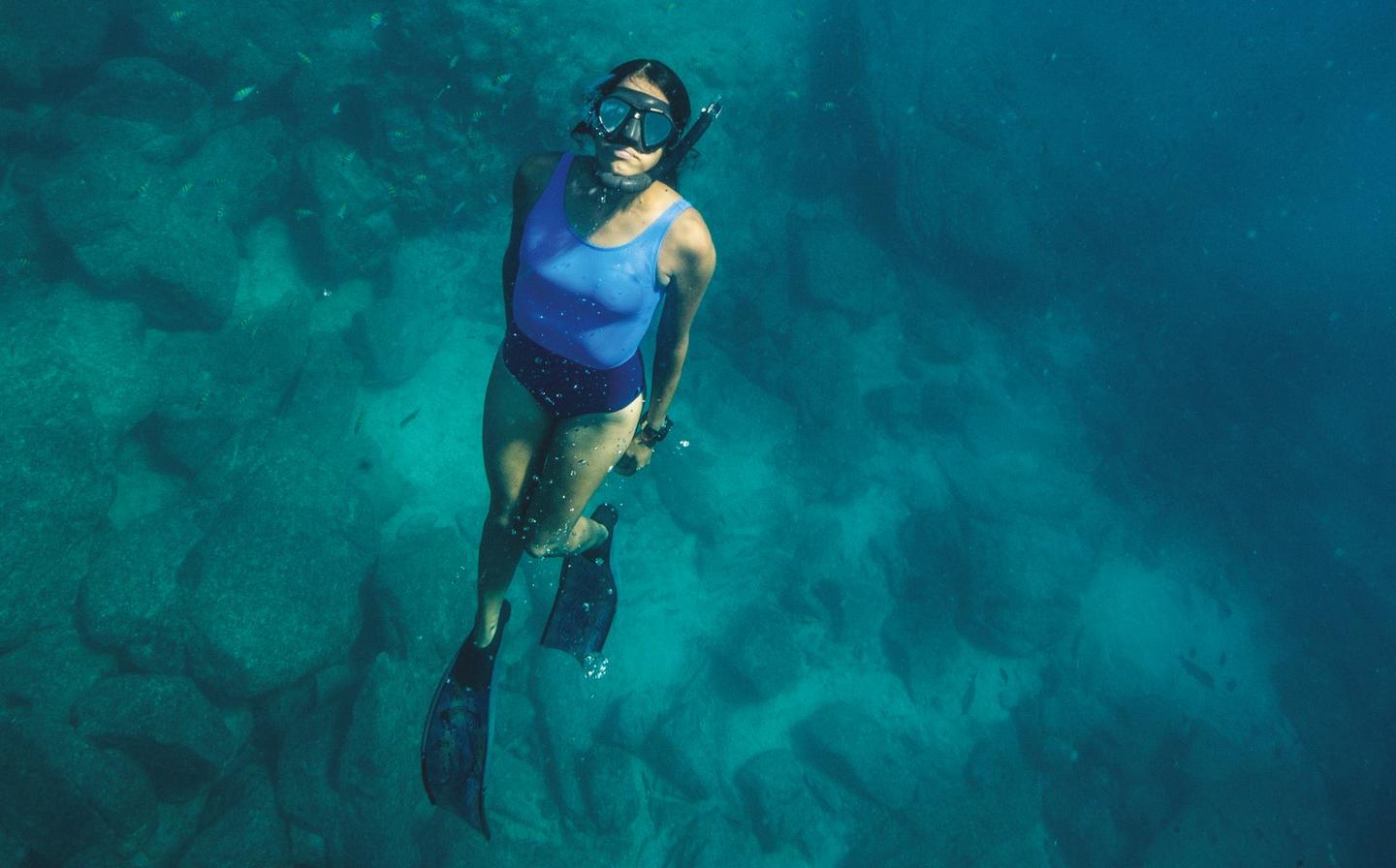 A female diver snorkels underwater and wears eco-friendly swimwear, available to buy at FatFace