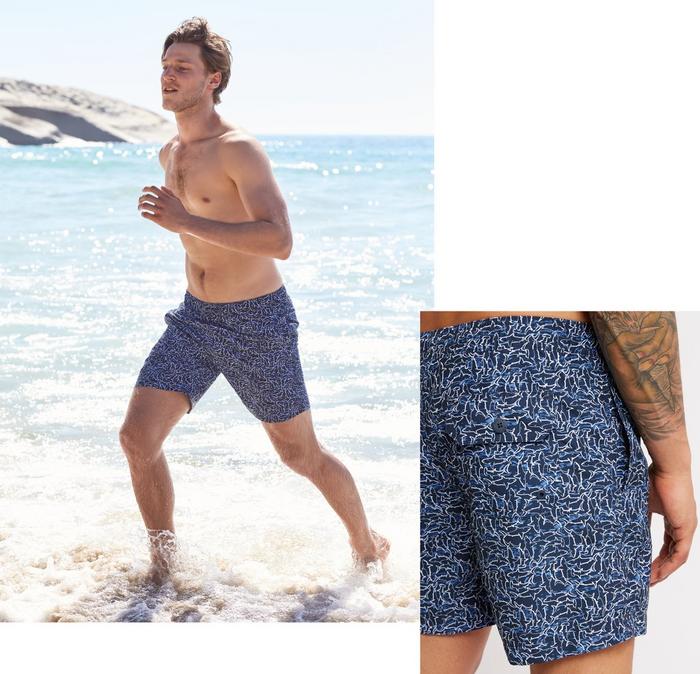 A man running along the seashore while wearing printed FatFace shorts