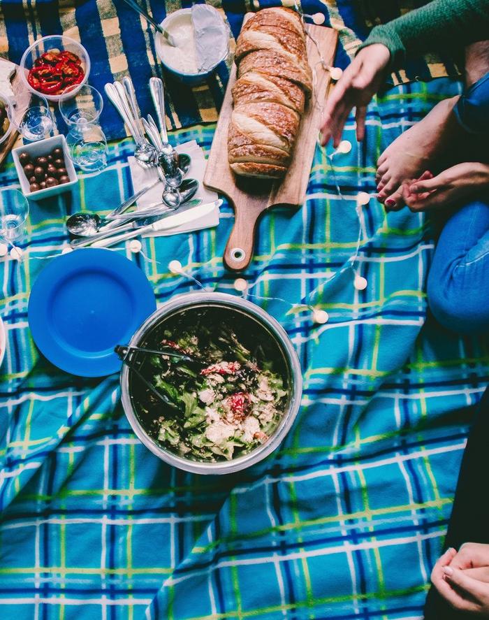 Food arranged on a blanket with people sat around whilst having an indoor picnic