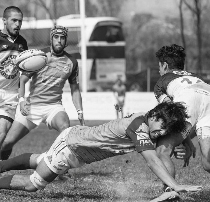 A rugby player tackling another player on the opposite side