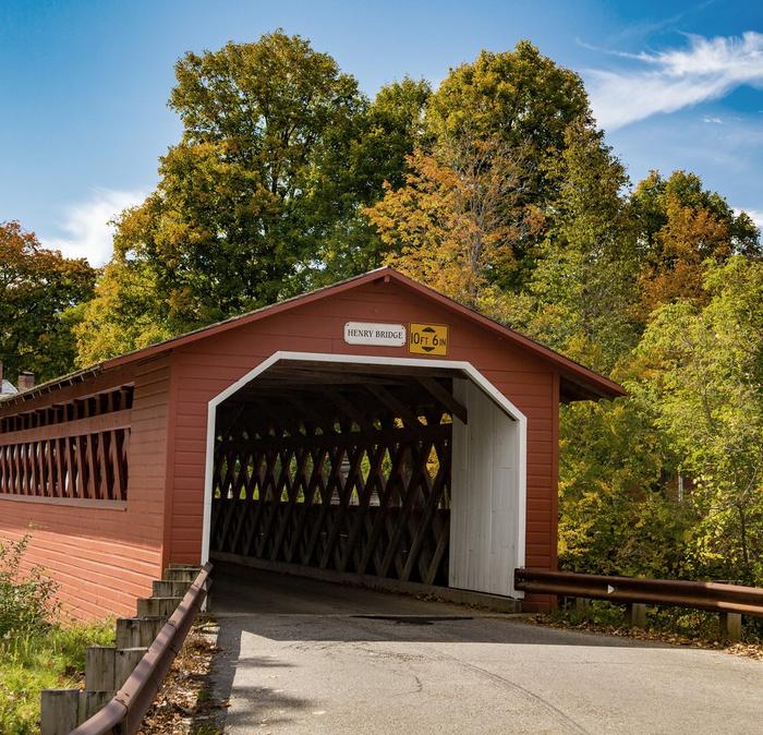A covered bridge tunnel in Bennington, Vermont with green trees in the background.