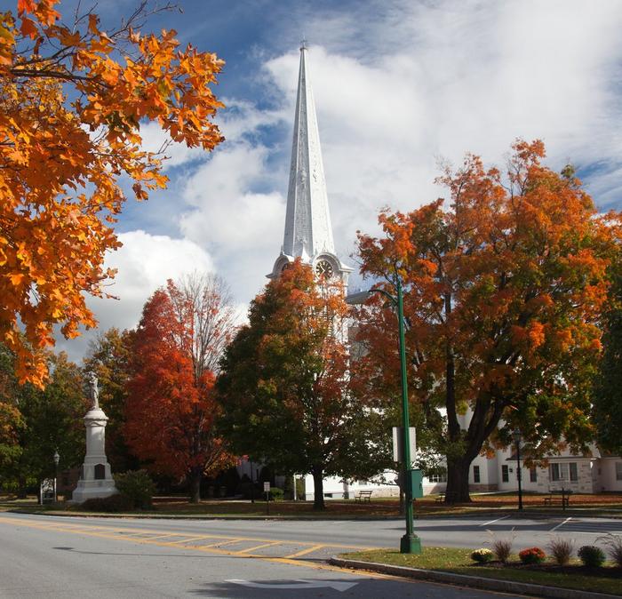 Autumnal orange leaved trees surrounding a road in Manchester, Vermont.