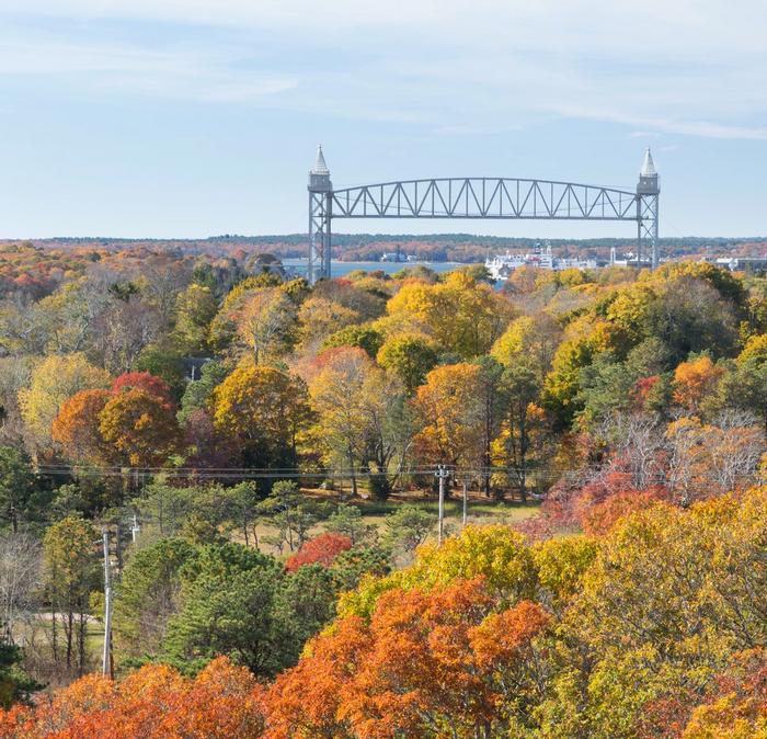 Sagamore Bridge in the background, behind a forest of orange and green autumnal trees