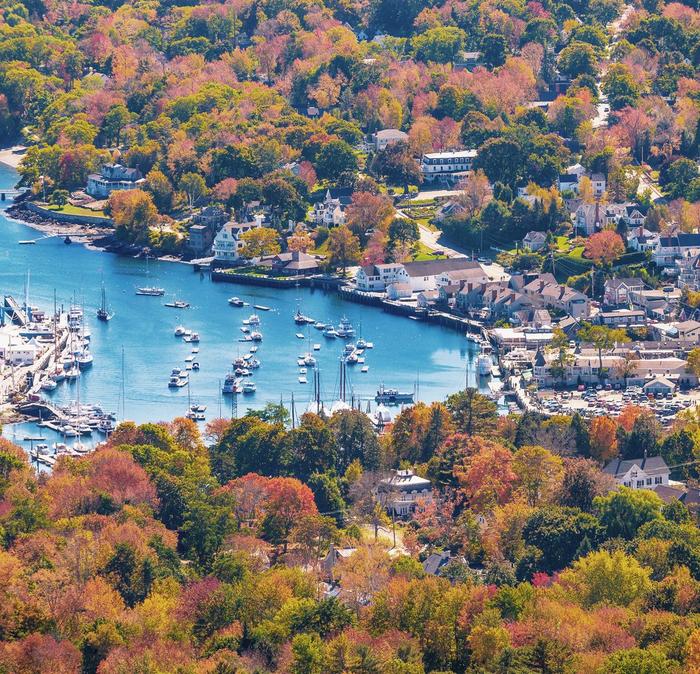 Autumn trees surrounding the blue Camden Harbour in Maine, USA.