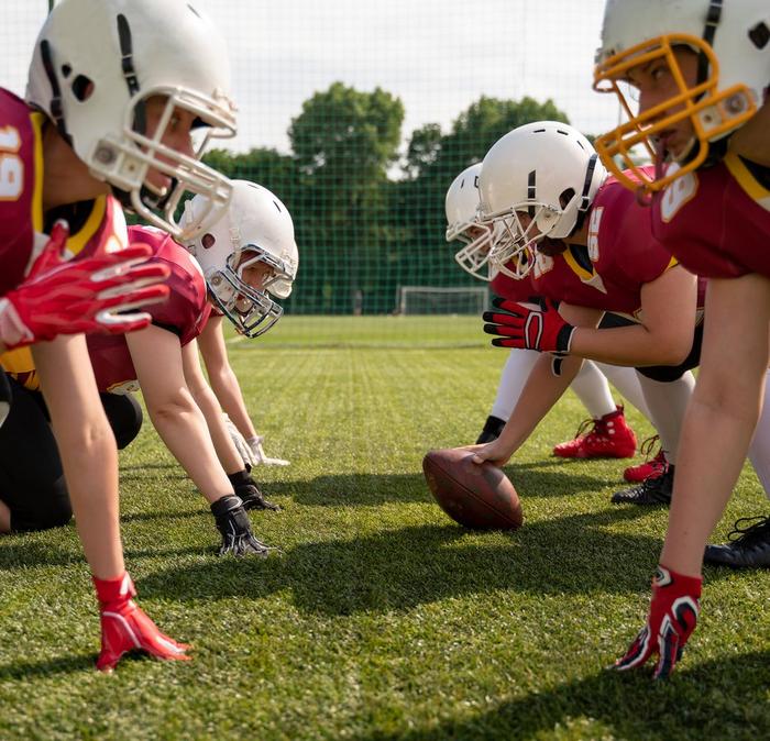 Two rows of people wearing American Football kits, crouched down ready to start a game.