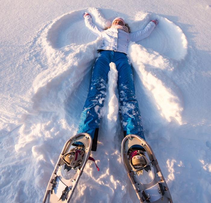 A girl lying in the snow making snow angels.