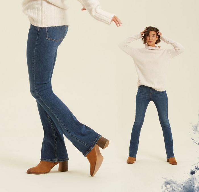 A female model wearing classic Selsey Bootcut Jeans with a white jumper and brown leather ankle boots.