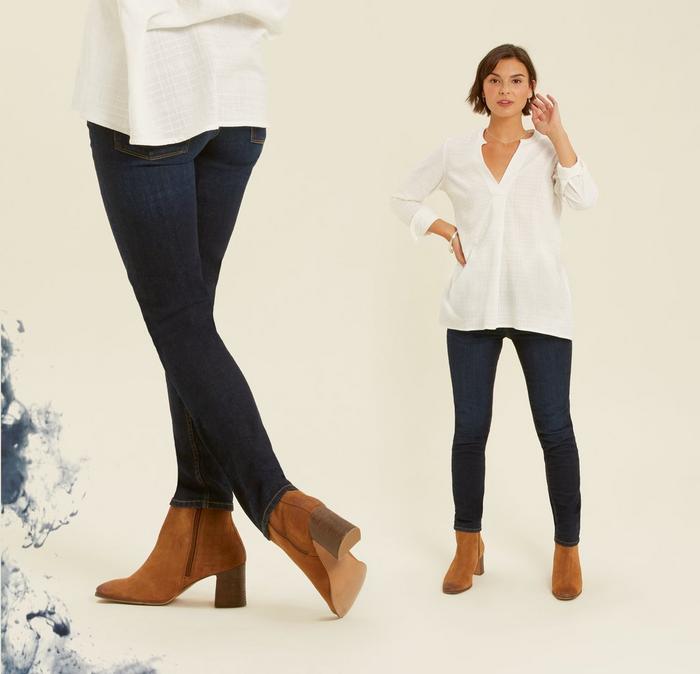 A female model wearing slim fitting Westbury jeans in blue wash denim, with a white shirt and brown ankle boots.
