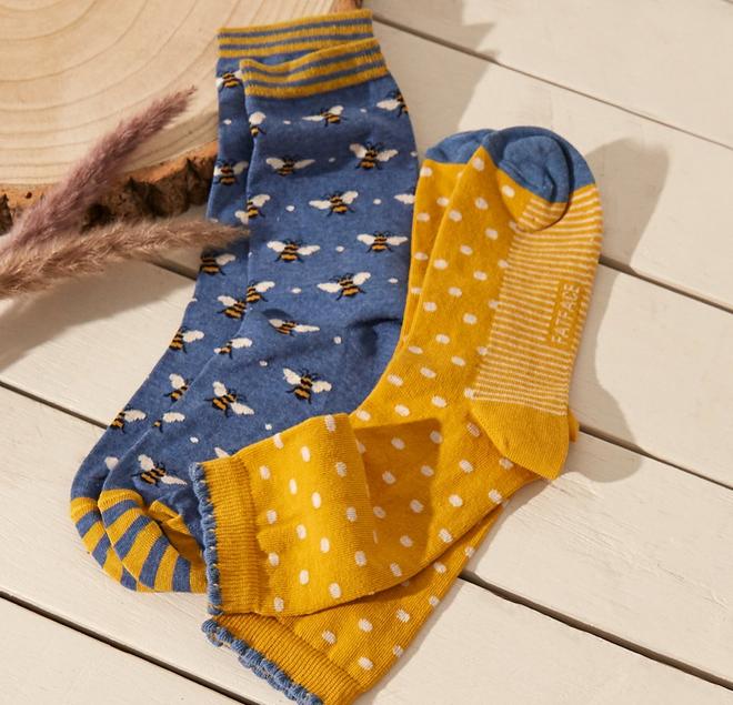 Two pairs of women's ankle socks, one blue with bee pattern print & one yellow with white polka dot print.