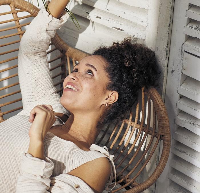 A woman relaxing in a wicker chair.