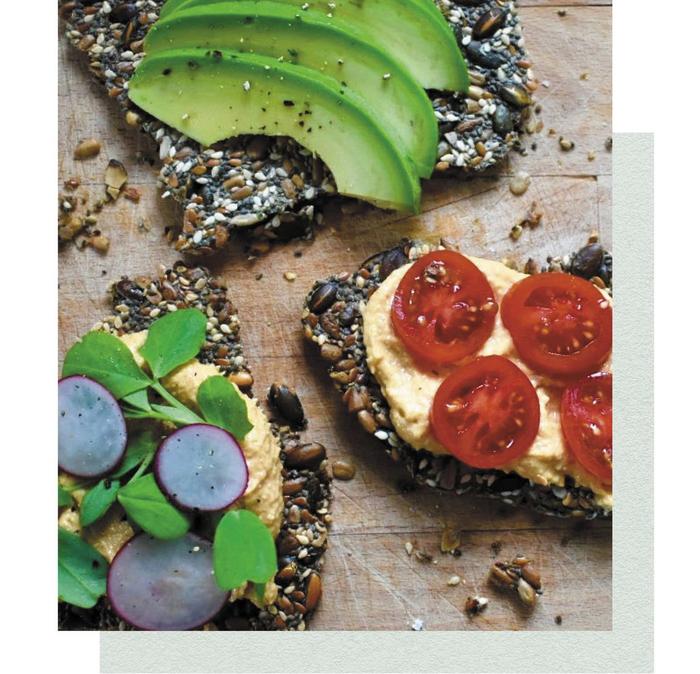 High-fibre crackers made from various seeds, topped with sliced avocado, radishes and cherry tomatoes.