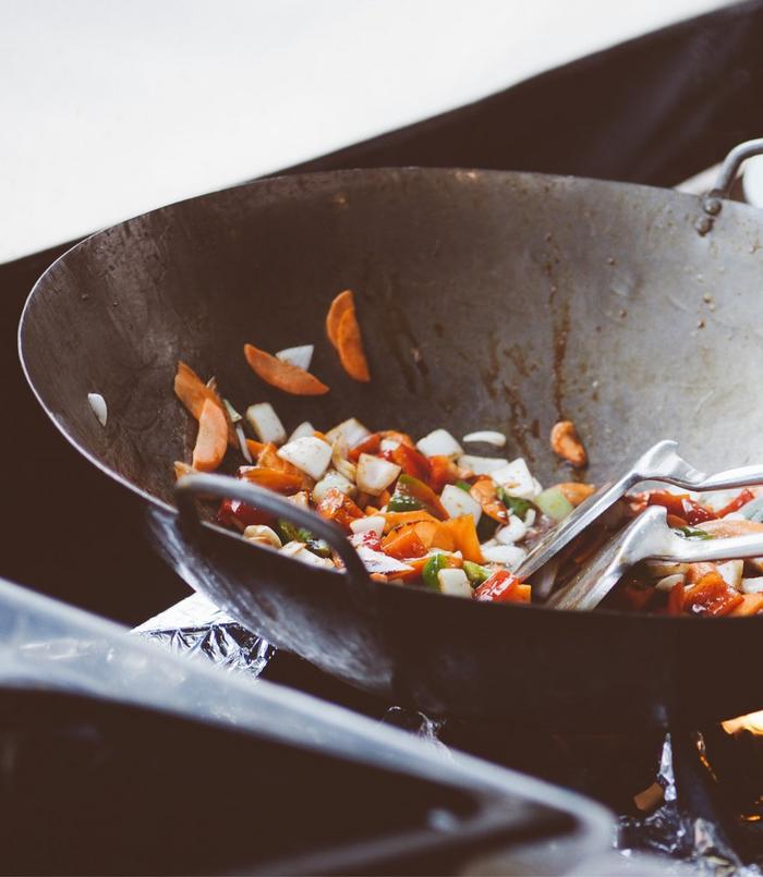 Multi-coloured healthy veggies being sautéd in a wok.