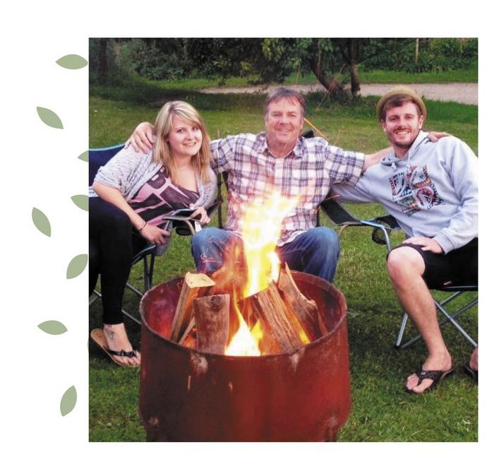 A family photo featuring Darren and his Dad sitting in folding chairs by a campfire.