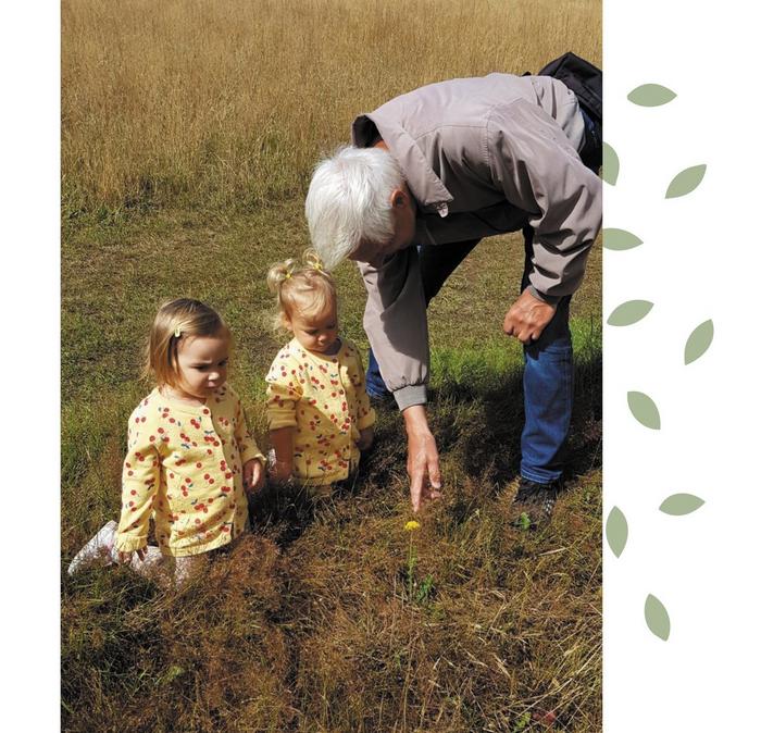 A family photo featuring Laura's Dad in a field with his two young granddaughters.