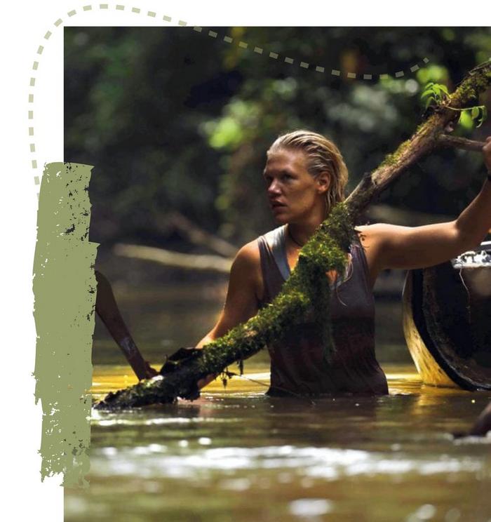 A woman wading through a river removing obstacles.