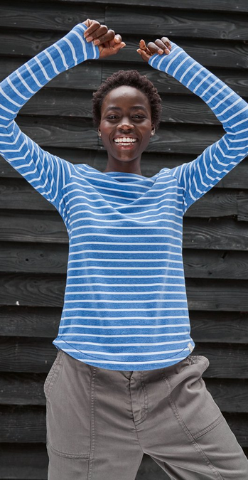 A woman wearing a long-sleeved blue T-shirt with white stripes, and khaki utility trousers.