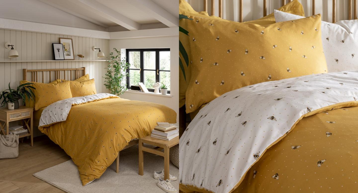 A modern bedroom with a double bed, made up with bee print bedsheets; mustard yellow one side, white on the reverse.