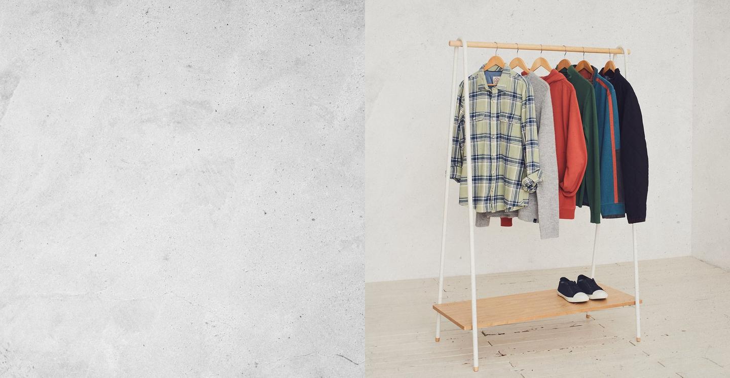 A range of men's clothes, including a check shirt, jumper, hoodie, sweatshirts & a jacket, hanging on a rail.