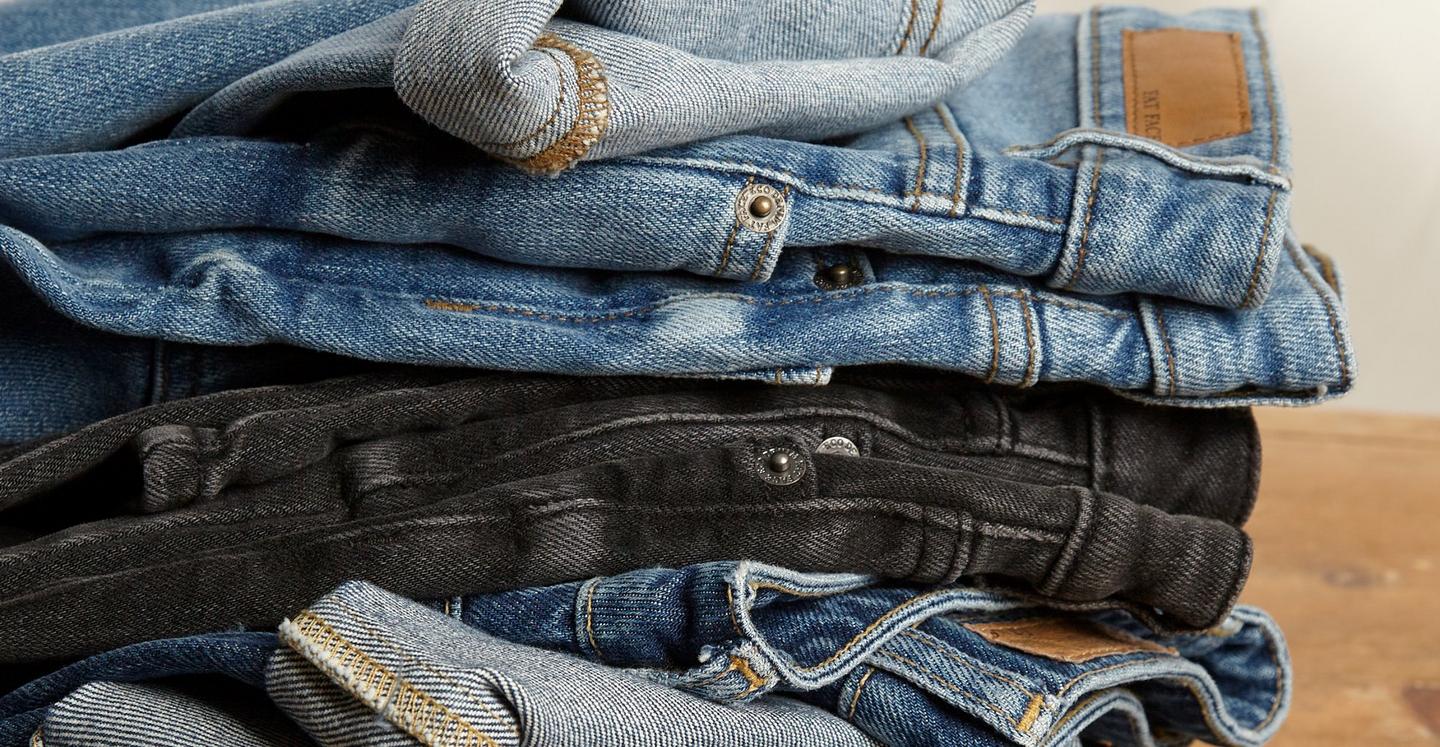 Close up on a stack of women's denim jeans in various blue & black washes.