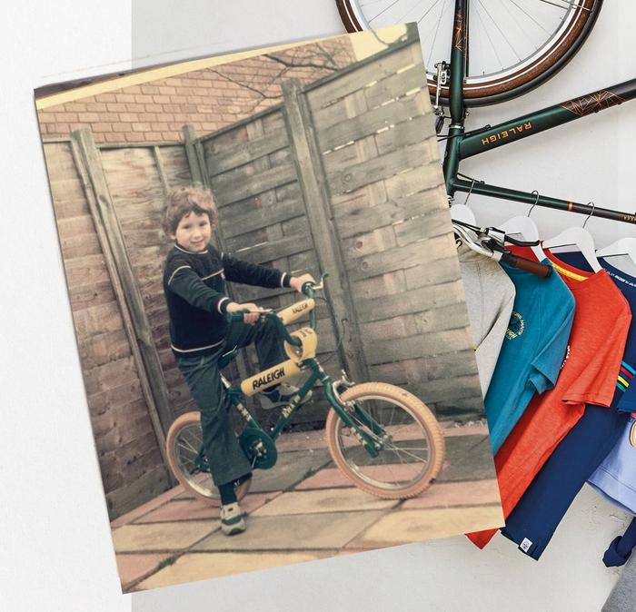 A faded home-photo of a young boy on a Raleigh bicycle, & a selection of colourful graphic tees hanging off a bike frame.