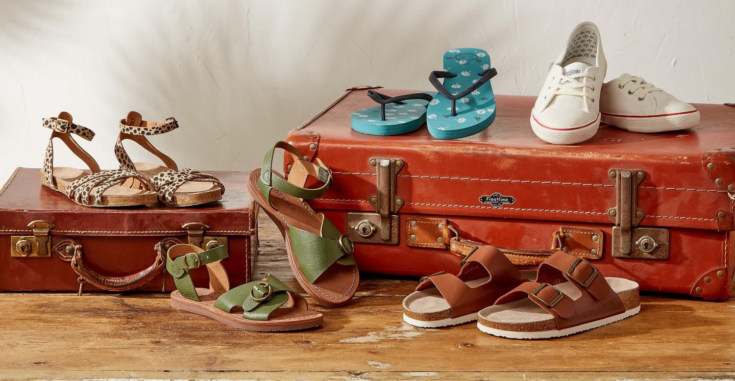 A collection of women's shoes - including strappy suede sandals, leather mules, floral flip flops & white trainers.