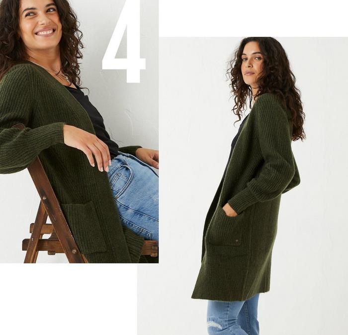 A woman wearing a dark green relaxed fit longline cardigan, over a black T-shirt & blue jeans.