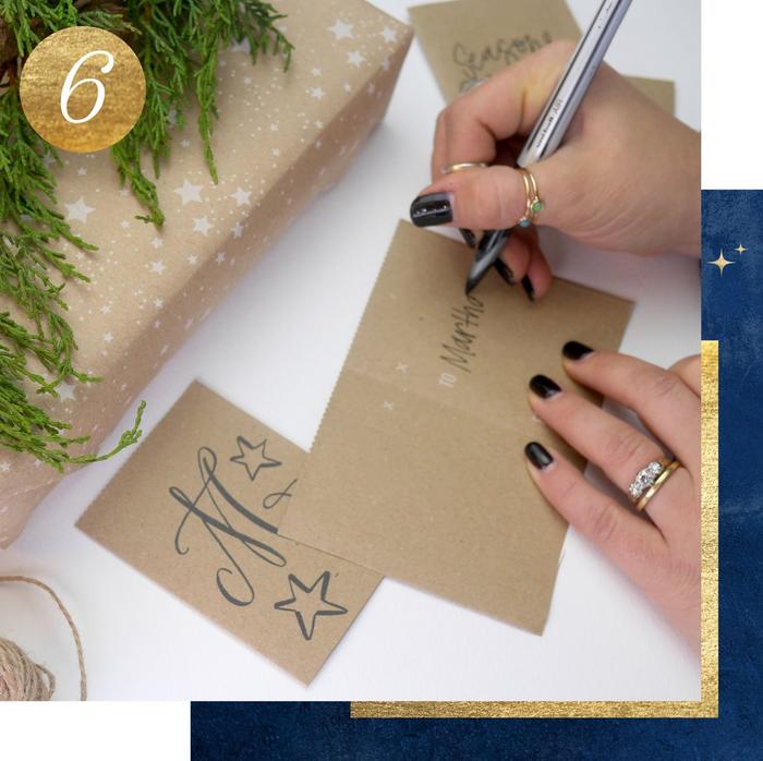 Step 6. A woman writing a name on a cardboard gift tag with a stylish monogram on the front.