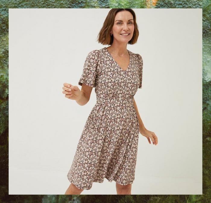 Woman modelling a sleeved floral wrap dress with covering floral pattern.