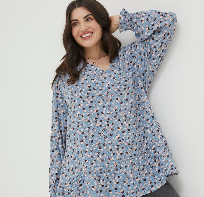 A woman wearing a long-sleeved sky-blue blouse with ditsy floral print & V-neck.