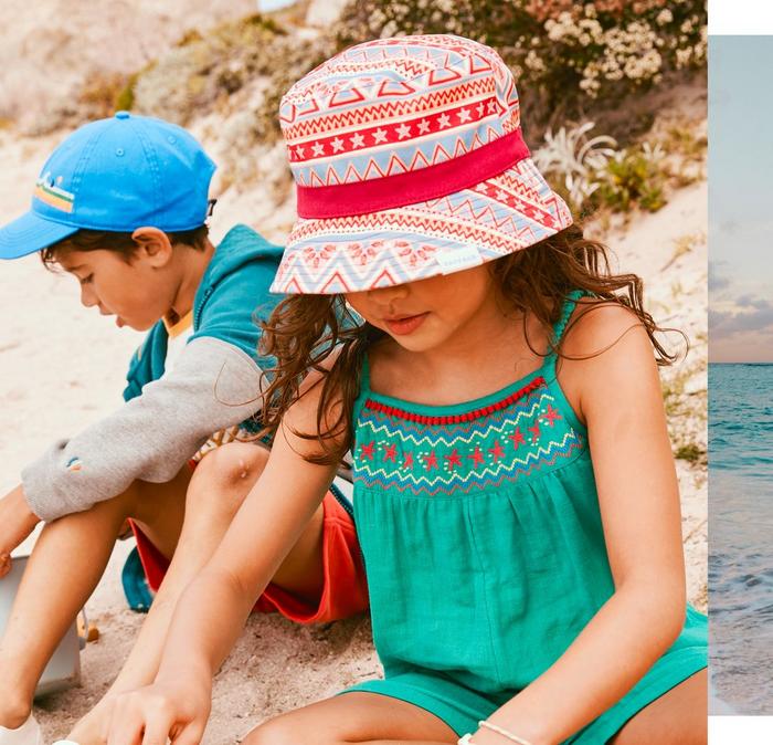A boy & a girl wearing colourful summer outfits complete with sun hats.