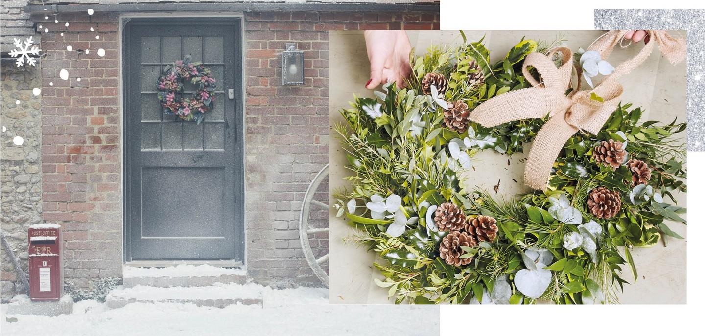 A Christmas wreath hanging on a door in the snow. A wreath made of winter foliage, & decorated with a hessian bow & pinecones.