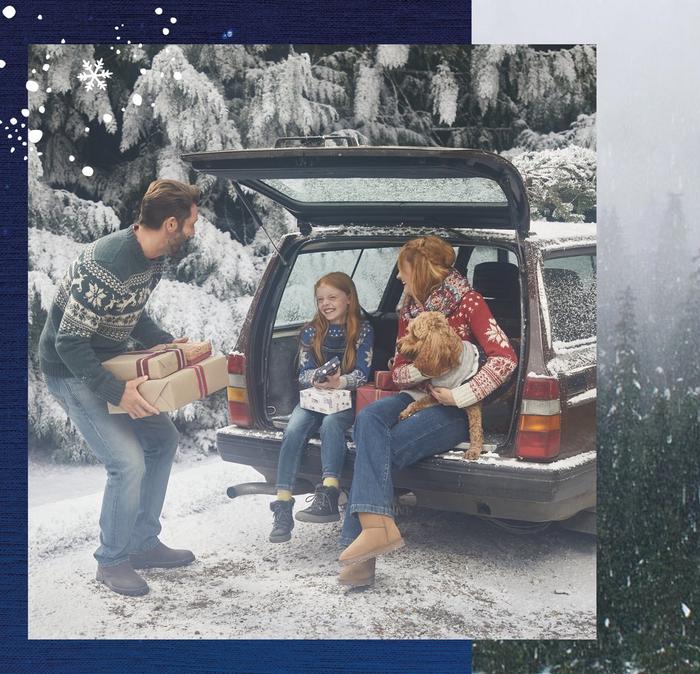 A family in Christmas sweaters & jeans, putting gifts in a car in the snow.