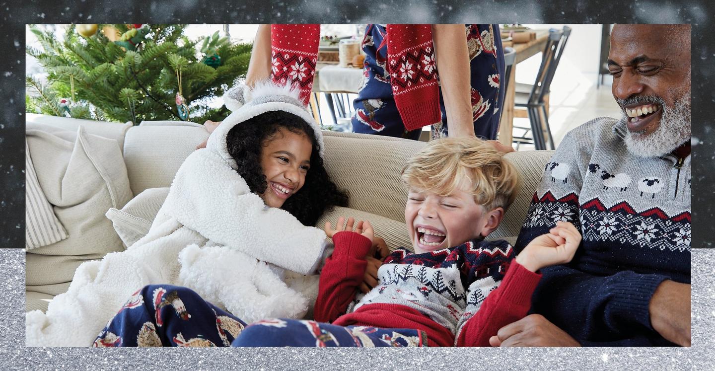 A family wearing cosy red navy & white nightwear & knitwear featuring Stevie the Sheep character.