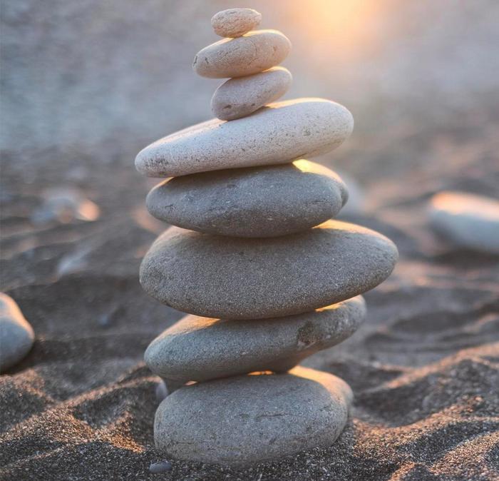 A stack of carefully balanced pebbles on a sandy beach.