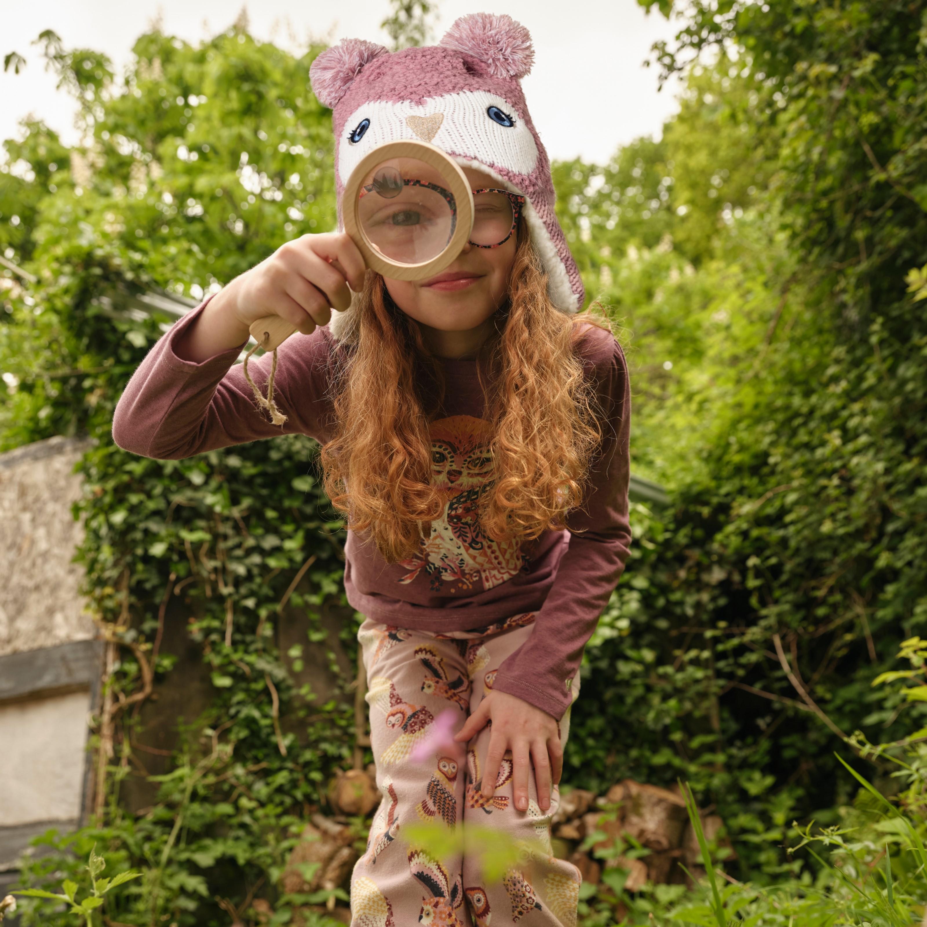 A girl wearing a pink beanie hat & a PJ set with a long-sleeved purple T-shirt & pale pink bottoms, all with owl graphics.