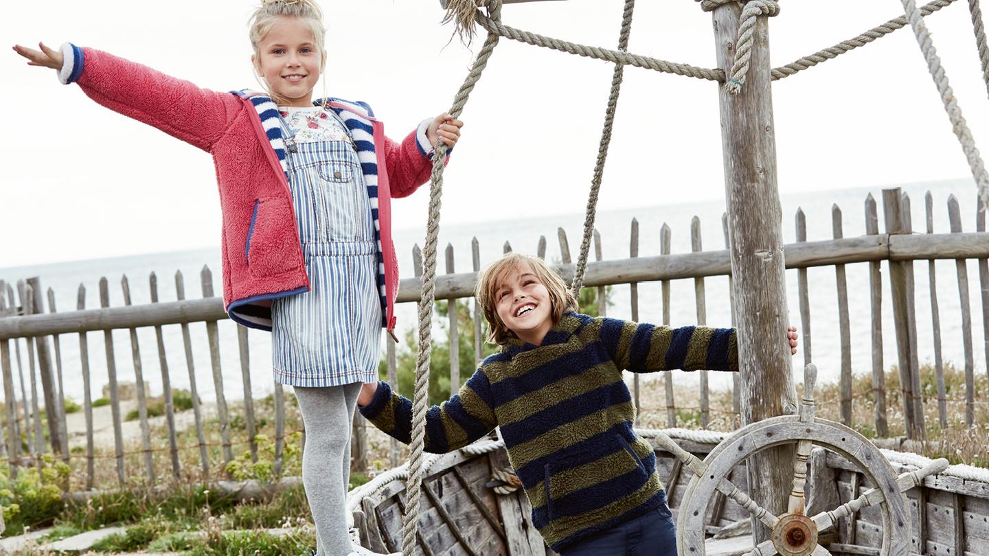 Two child models playing on a wooden pirate ship in the garden